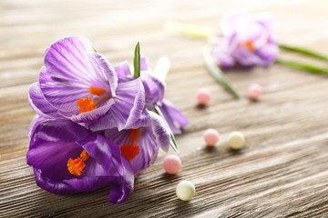 Obraz na płótnie Canvas Beautiful crocus flowers with beads on wooden table closeup