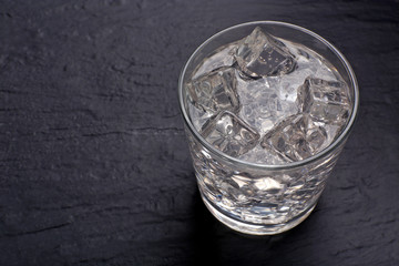Glass of soda with ice on dark table
