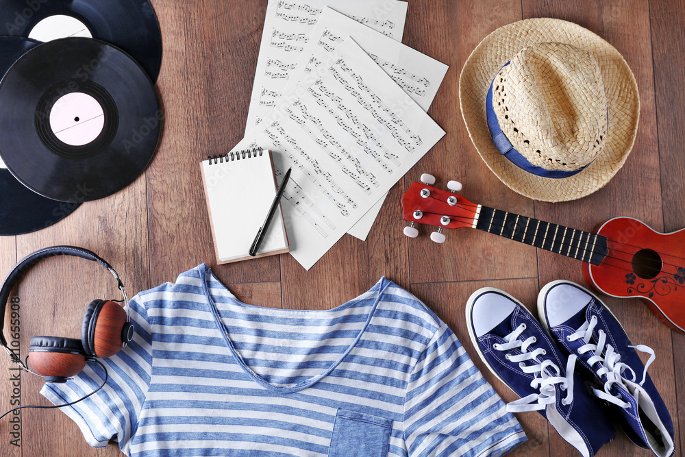 Wall mural guitar, headphones, music sheets and clothes on wooden surface, top view