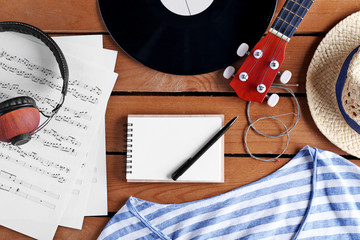 Guitar, headphones and music sheets on wooden surface, top view