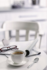 White cup of the coffee on wooden table  in a light room..