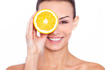 Good for my skin! A young attractive woman holding an piece of orange and smiling at the camera.