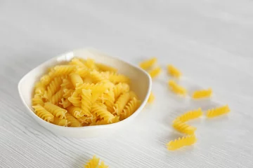 Fresh uncooked pasta in bowl on wooden table closeup