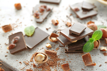Pieces of chocolate with hazelnuts and fresh mint on light background