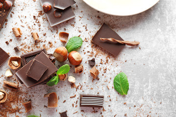 Pieces of chocolate with hazelnuts and fresh mint on light background