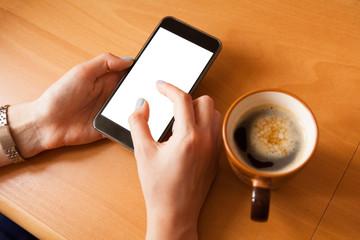Mobile phone mockup. Female hands with smartphone with copy space on screen and cup of coffee. Fingers zooming in picture on screen. Online store concept.