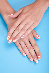 Closeup photo of a beautiful female hands with manicure on a blue background
