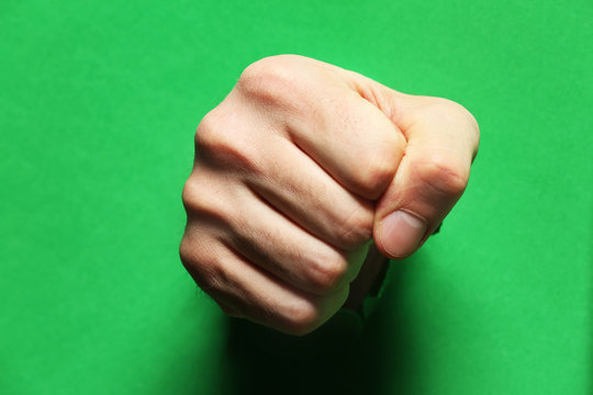 Male Fist Punching Through Green Paper