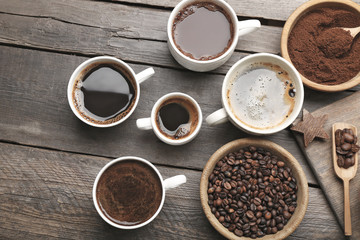 Cups of coffee with spices on wooden table, top view