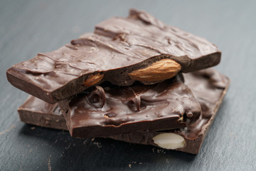 homemade chocolate with almond nuts in stack on slate board, shallow focus