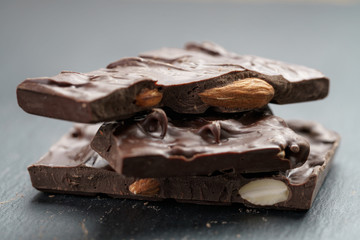 homemade chocolate with almond nuts in stack on slate board, shallow focus
