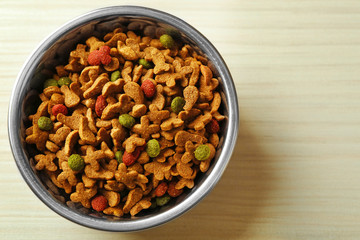 Dog food in metal bowl on wooden background