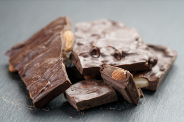 reverse side homemade chocolate with almond nuts on slate board, shallow focus