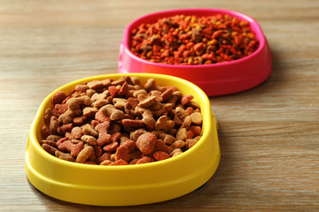 Dog food in plastic bowls on wooden background