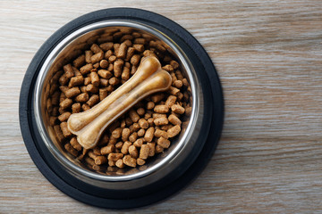 Dog food in metal bowl on wooden background