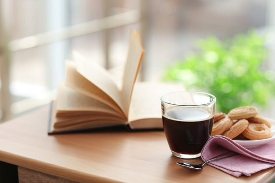 Fototapeta Cup of coffee and book on the table in cafe