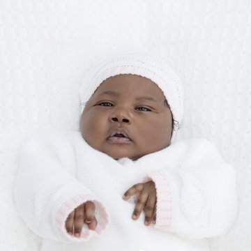 Adorable one-month-old baby girl lying in her bed