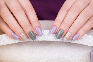 Obraz na płótnie Canvas Manicure - Beauty treatment photo of nice manicured woman fingernails. Very nice feminine nail art with nice purple,silver and grayish nail polish. 