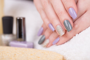 Manicure - Beauty treatment photo of nice manicured woman fingernails. Very nice feminine nail art with nice purple,silver and grayish nail polish. 