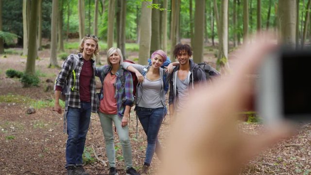 Group of friends hiking in the woods pose to take a photograph. 