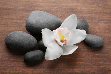 Fototapeta na wymiar Stones and white orchid on wooden background