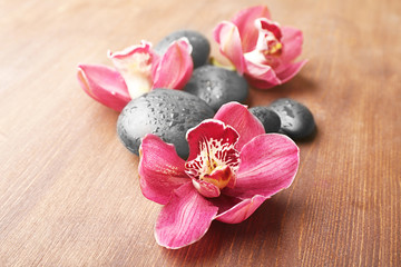 Stones and red orchid on wooden background