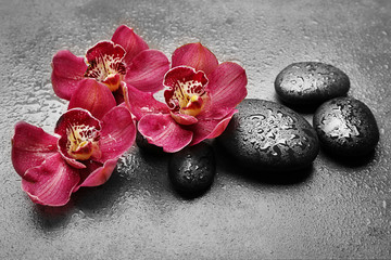 Spa stones and red orchid on grey background