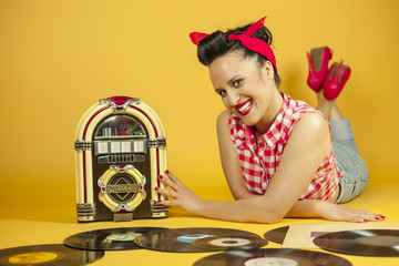 Portrait beautiful pin up listening to music on an old jukebox r