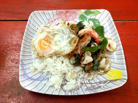Rice with stir fried spicy seafood with fried egg