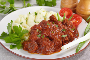 Goulash with mashed potatoes and tomato