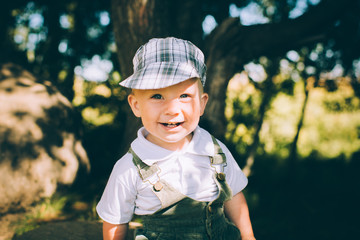 The little boy in overalls and a cap on the nature