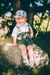 The little boy in overalls and a cap on the nature