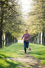 Young woman running with her dog sheltie in the park and training her shetland sheepdog