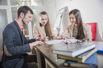 three students communicate young businessman looking at documents sitting in the office