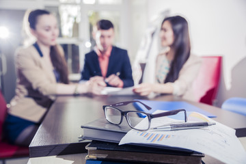 Obraz premium financial chart near dollars seen by unfocused glasses ( colleagues meeting to discuss their future financial plans only silhouettes being viewed )
