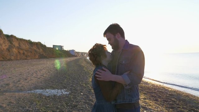 happy loving couple hugging on beach in sun beams, slow motion