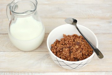 Chocolate muesli with milk in the glass jug on the wooden background