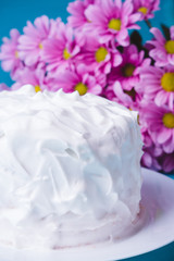 Obraz na płótnie Canvas White creamy cake with flowers on the blue wooden background