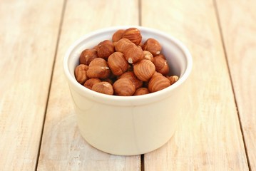 Hazelnuts in the bowl on the wooden background