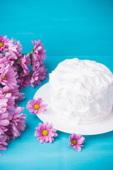 White creamy cake with flowers on the blue wooden background