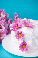 Obraz na płótnie Canvas White creamy cake with flowers on the blue wooden background