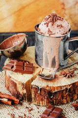 cold refreshing summer dessert , chocolate ice cream with cocoa, mint and cinnamon in an iron mug on a wooden background , rustic style