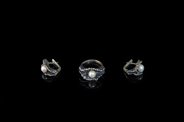 Ring and earrings of silver in the form of oysters with pearls on a black background