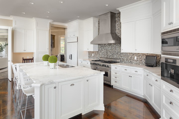 Kitchen in New Luxury Home with White Cabinets, Hardwood Floors, and Stainless Steel Appliances