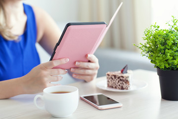 woman with pink phone reading the e-book in a cafe