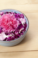 cropped image of pink carnation in bowl of carnation petals