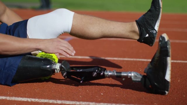  Disabled athlete with prosthetic leg warming up at running track