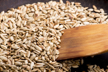sunflower seeds, roasted sunflower seeds in a frying pan with a wooden spatula.