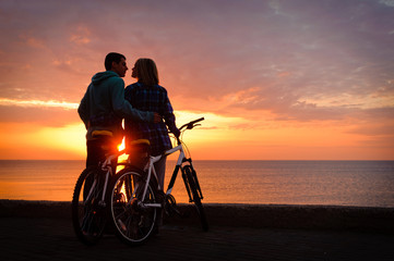 Obraz na płótnie Canvas Couple of cyclists at the beach at sunset.