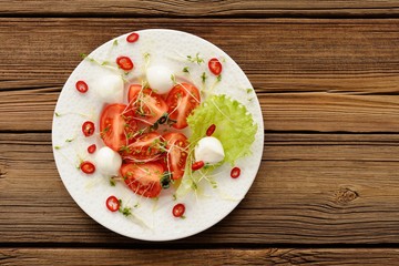 Salad made of fresh tomatoes, chili pepper, mozarella and watercress